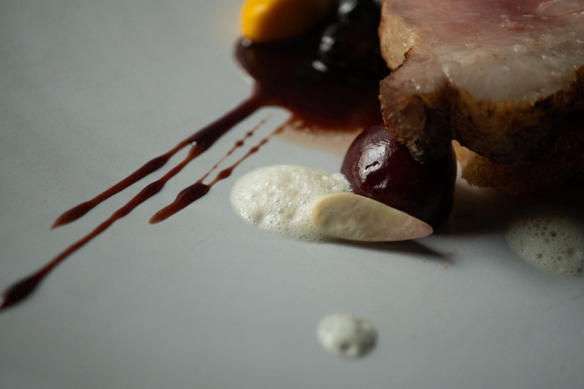 Meat dish plated with chocolate sauce and crisp elements