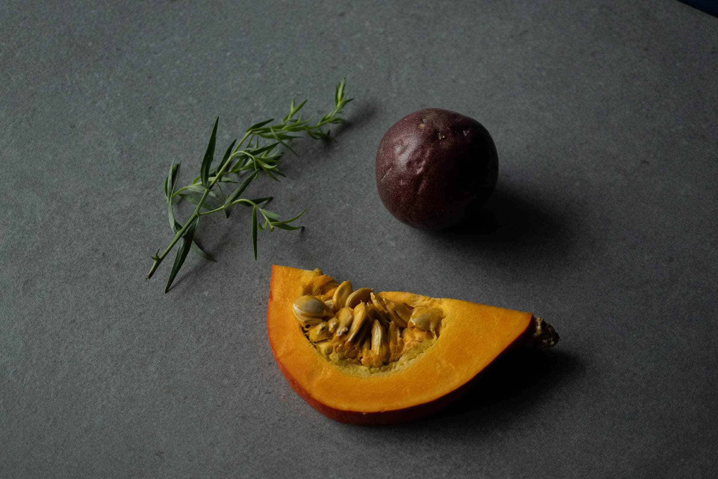 Still life: butternut squash slice, passion fruit and fresh herb sprig